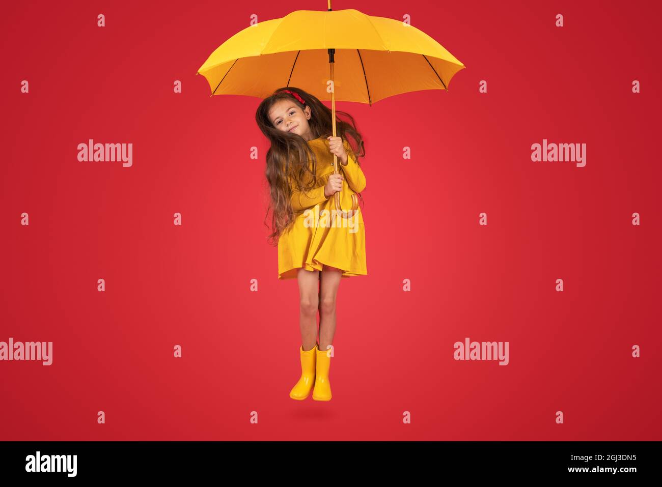 Bonne fille émotive riant avec parapluie sur fond rouge coloré. Automne, printemps. Banque D'Images