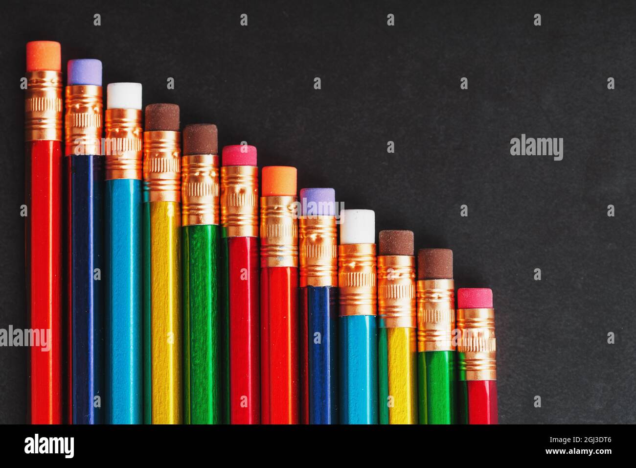 Crayons multicolores pour dessiner et dessiner en ligne sur un arrière-plan noir texturé en ligne. Vue de dessus, espace libre Banque D'Images