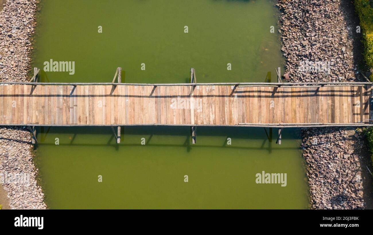 Pont en bois, avec main courante, dans un lac à eau verdâtre, en image de drone Banque D'Images