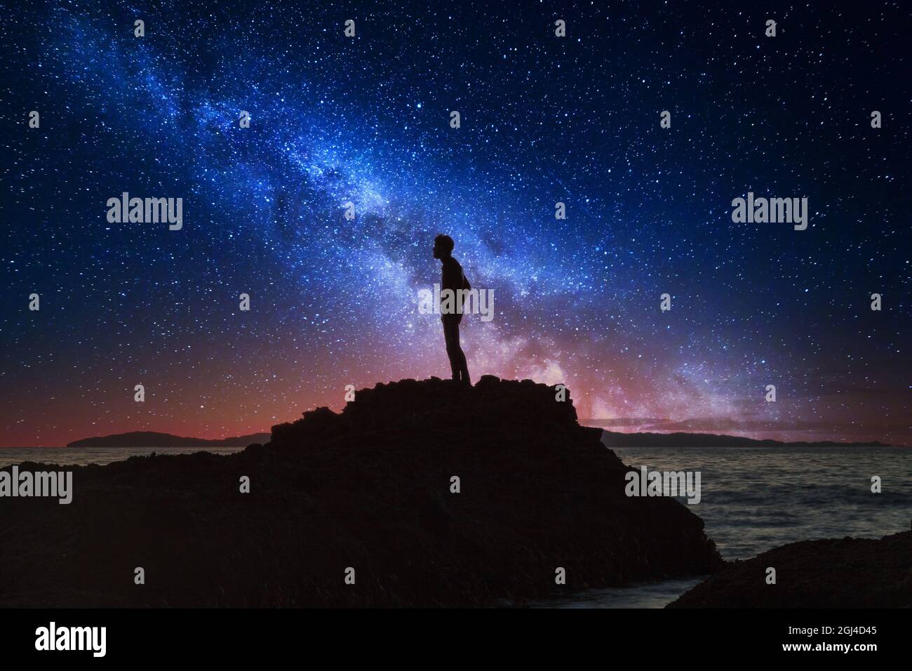 Des étoiles de nuit surent la silhouette de réflexion de l’homme sur l’eau de l’océan tandis qu’elle se cascade sur les rochers de Reykjavik, en Islande. Banque D'Images