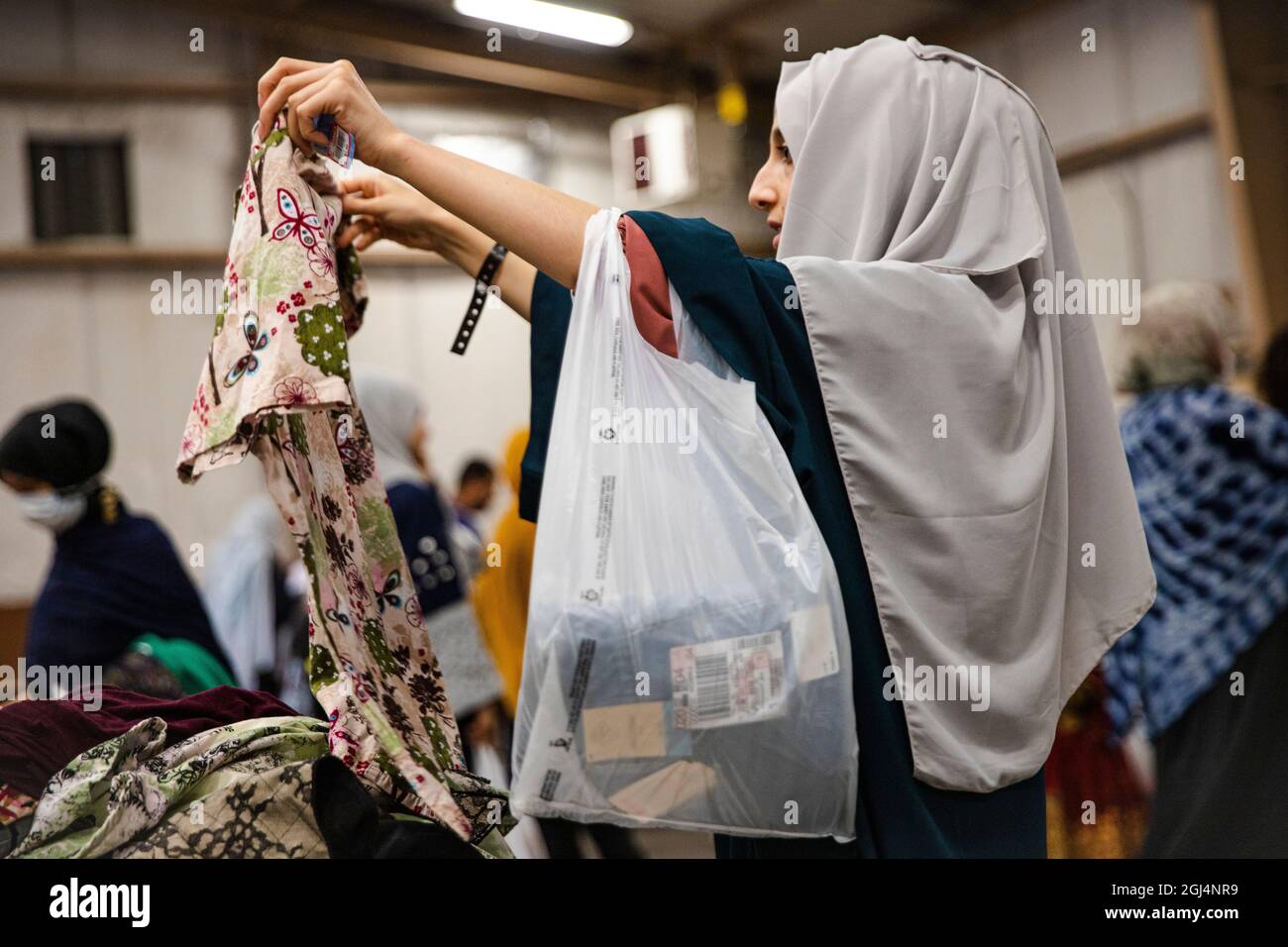 Fort McCoy, États-Unis. 07septembre 2021. Une femme afghane évacuée de Kaboul regarde à travers des vêtements donnés à fort McCoy le 7 septembre 2021 à fort McCoy, Wisconsin, États-Unis. McCoy est l'une des nombreuses installations militaires qui fournissent des logements temporaires aux Afghans lorsqu'ils sont traités pour l'immigration. Crédit: SPC. Rhianna Ballenger/Armée américaine/Alamy Live News Banque D'Images