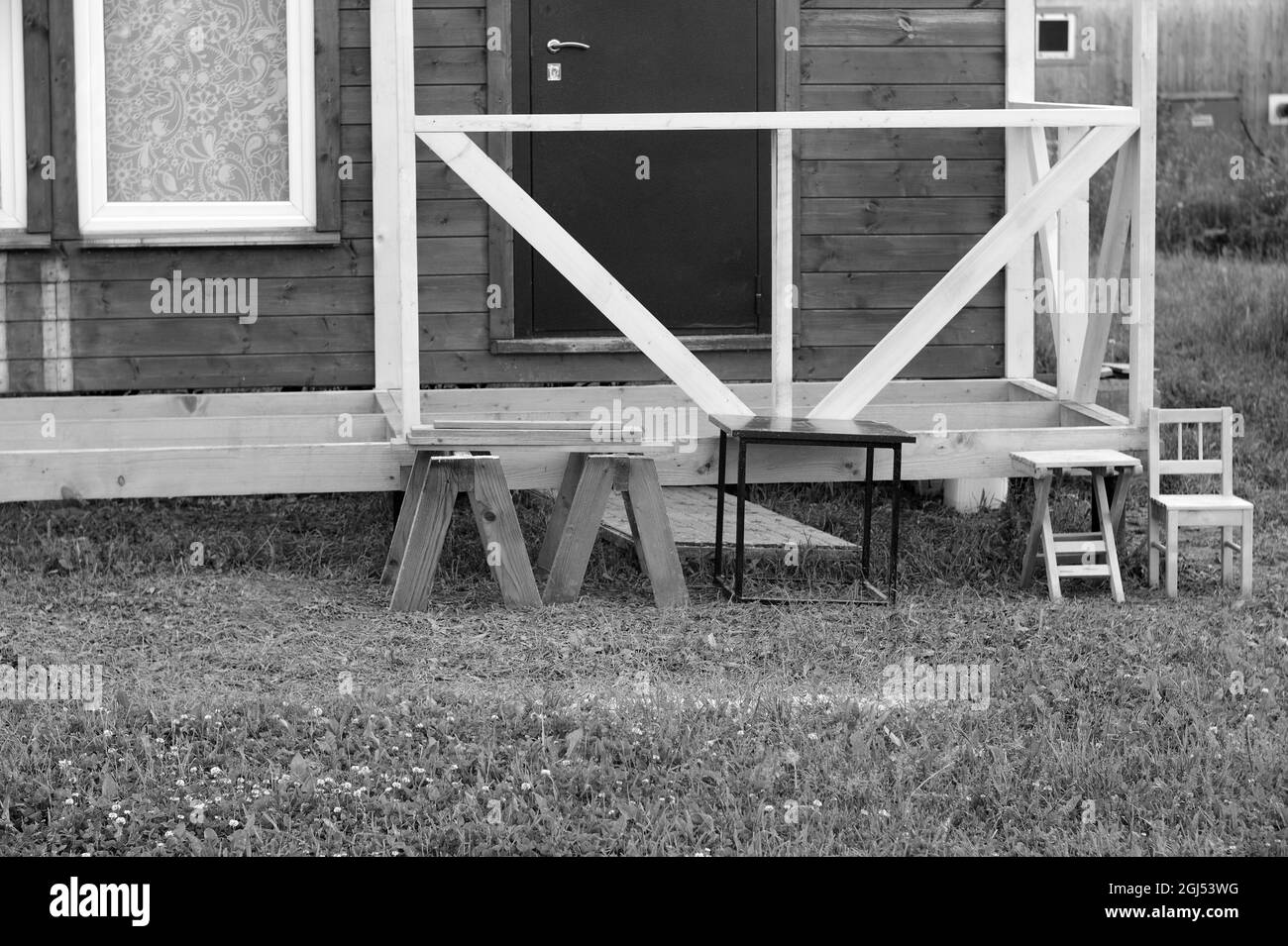 une petite maison d'été en bois avec des chaises placées à l'avant, en noir et blanc Banque D'Images