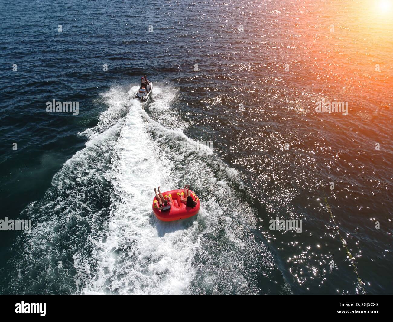 Des gens heureux vont nager sur un matelas pneumatique derrière un jet ski.  Les touristes se rendent sur le bateau gonflable. Attraction de la mer.  Patinage en jet ski Photo Stock -