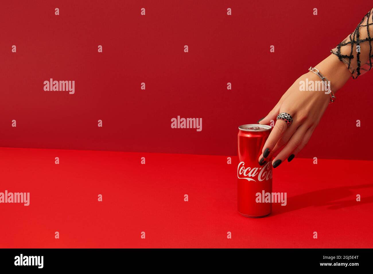 Ukraine, Kiev 6 août 2021, main de Womans avec la conception d'ongle effrayante prend CAN de boisson Coca cola sur fond rouge. Banque D'Images