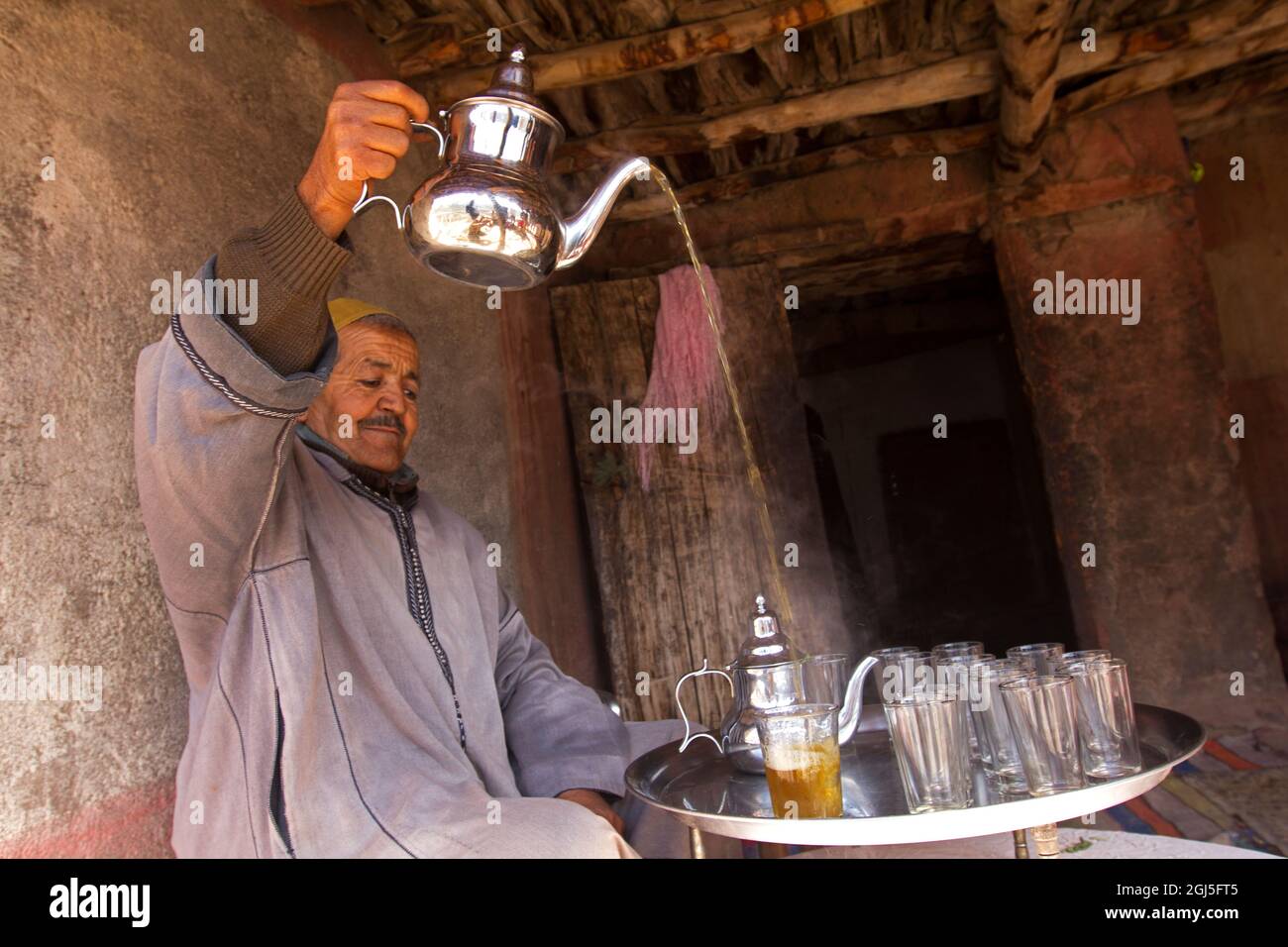 Afrique, Maroc, Asni. Berber homme versant le thé à la maison dans le village d'Asni dans les montagnes de l'Atlas. Banque D'Images