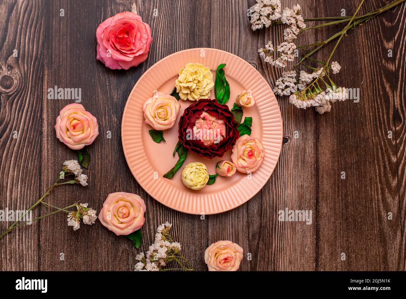 Roses rose chocolat, roses blanches, pivoines sur fond de bois sombre. Banque D'Images