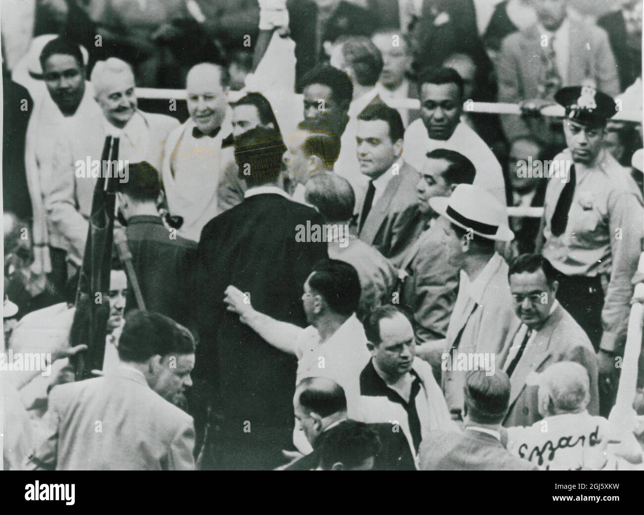 L'arbitre Dave Miller (centre gauche , arrière-plan) lève Ezzard Charles , main pour le déclarer , gagnant , tandis que sur la gauche une civière est brouilleuse dans le ring pour porter salut Manager , Jake Mintz . 24 juin 1949 Banque D'Images