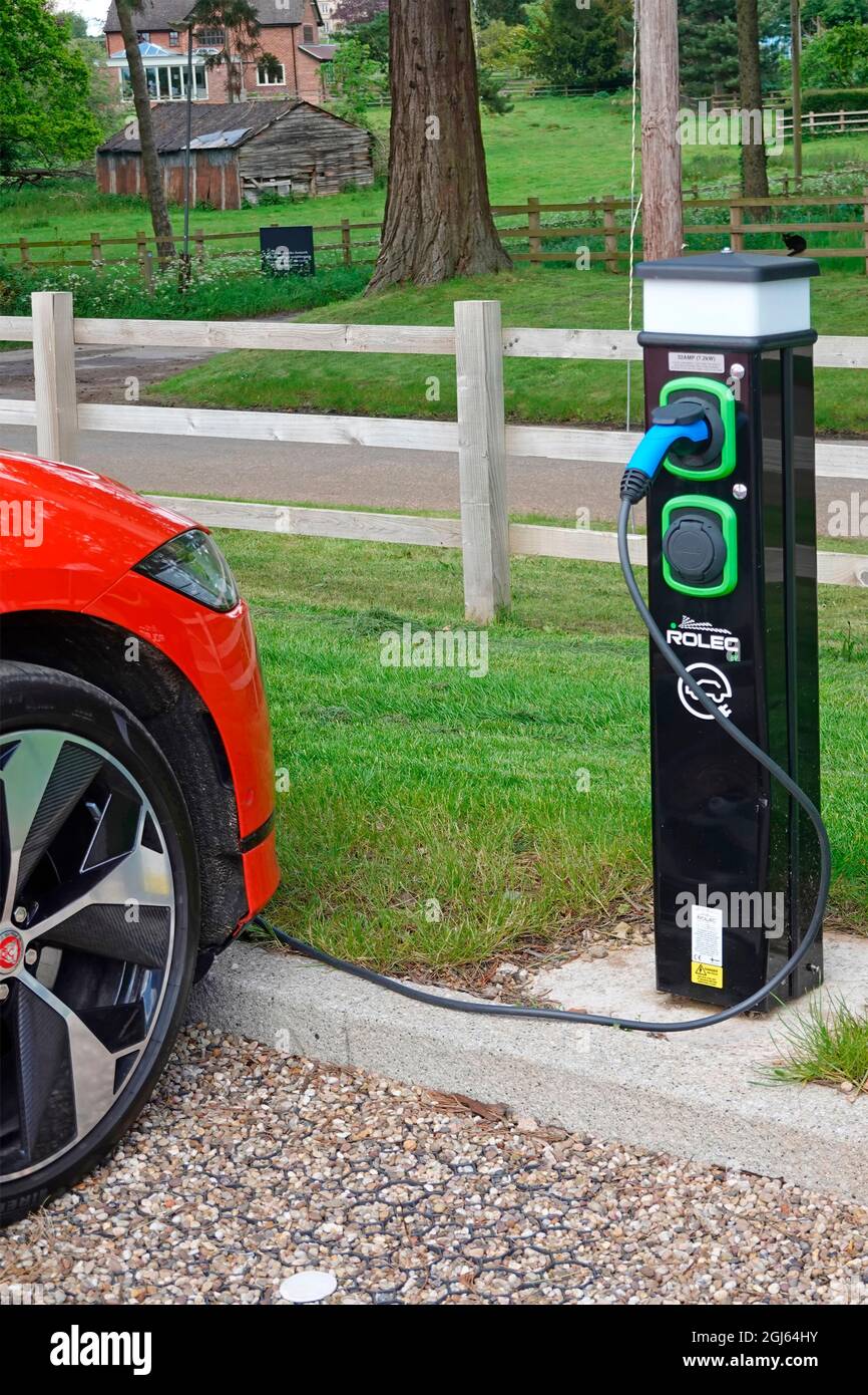 Gros plan voiture électrique rouge Jaguar et câble électrique relié à la charge bollard un établissement à Warners Leisure Hotel Studley Warwickshire Angleterre Royaume-Uni Banque D'Images