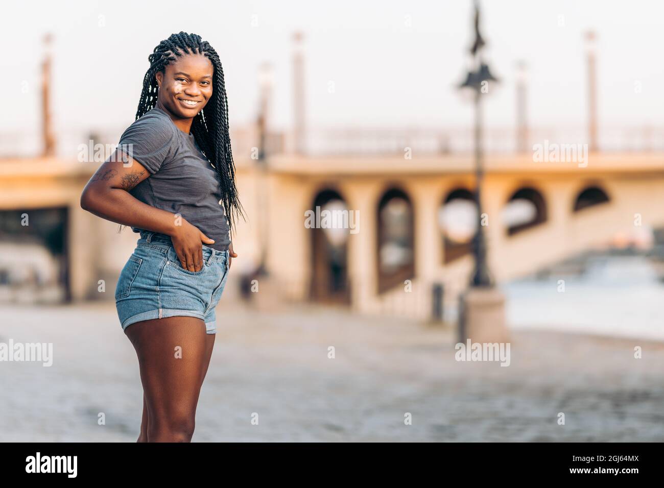 Femme noire avec tatouages debout à l'extérieur avec les mains dans les poches Banque D'Images