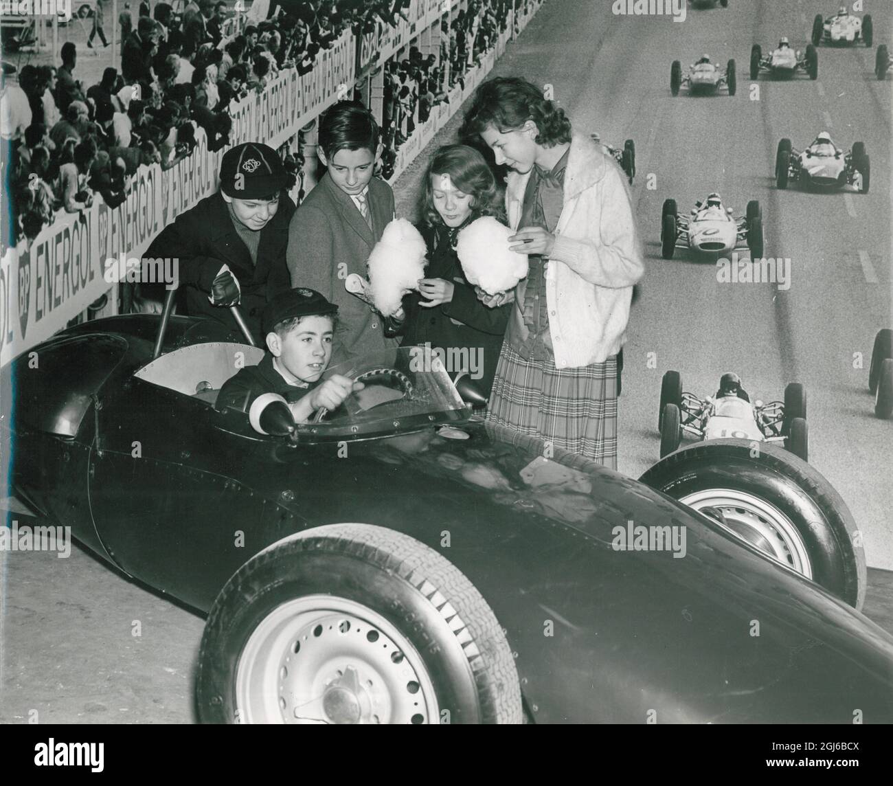 Clive Thompson, âgée de 11 ans, au volant d'un BRM - British Racing Motors , sur le stand Shell Mex et BP Ltd , regardée par d'autres jeunes visiteurs à l'exposition garçons et filles du Daily Mail à Olympia , Londres , Angleterre, le 28 décembre 1962 Banque D'Images