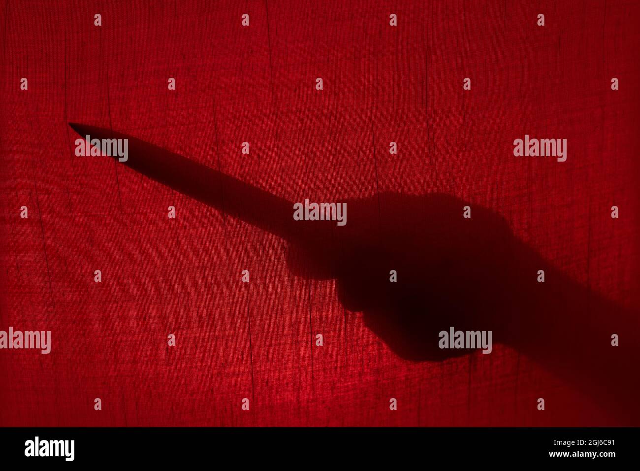 Main avec une silhouette de couteau derrière un rideau. Halloween et violence concept Banque D'Images