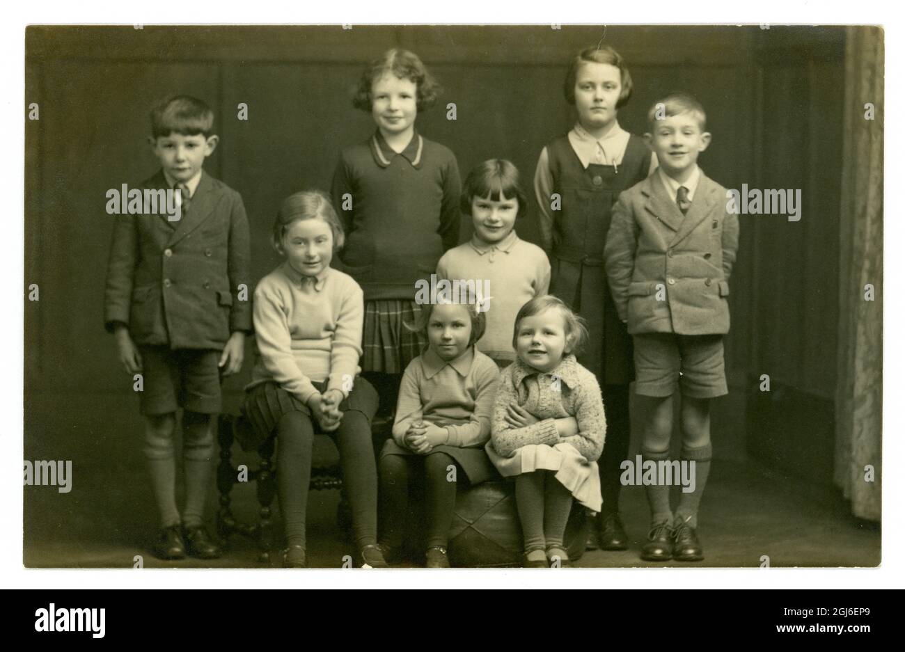 Image originale très claire de la carte postale de portrait de studio des années 1930 de 8 enfants, frères et sœurs ou cousins, uniformes scolaires, Lincoln, Angleterre,Royaume-Uni vers 1935 Banque D'Images