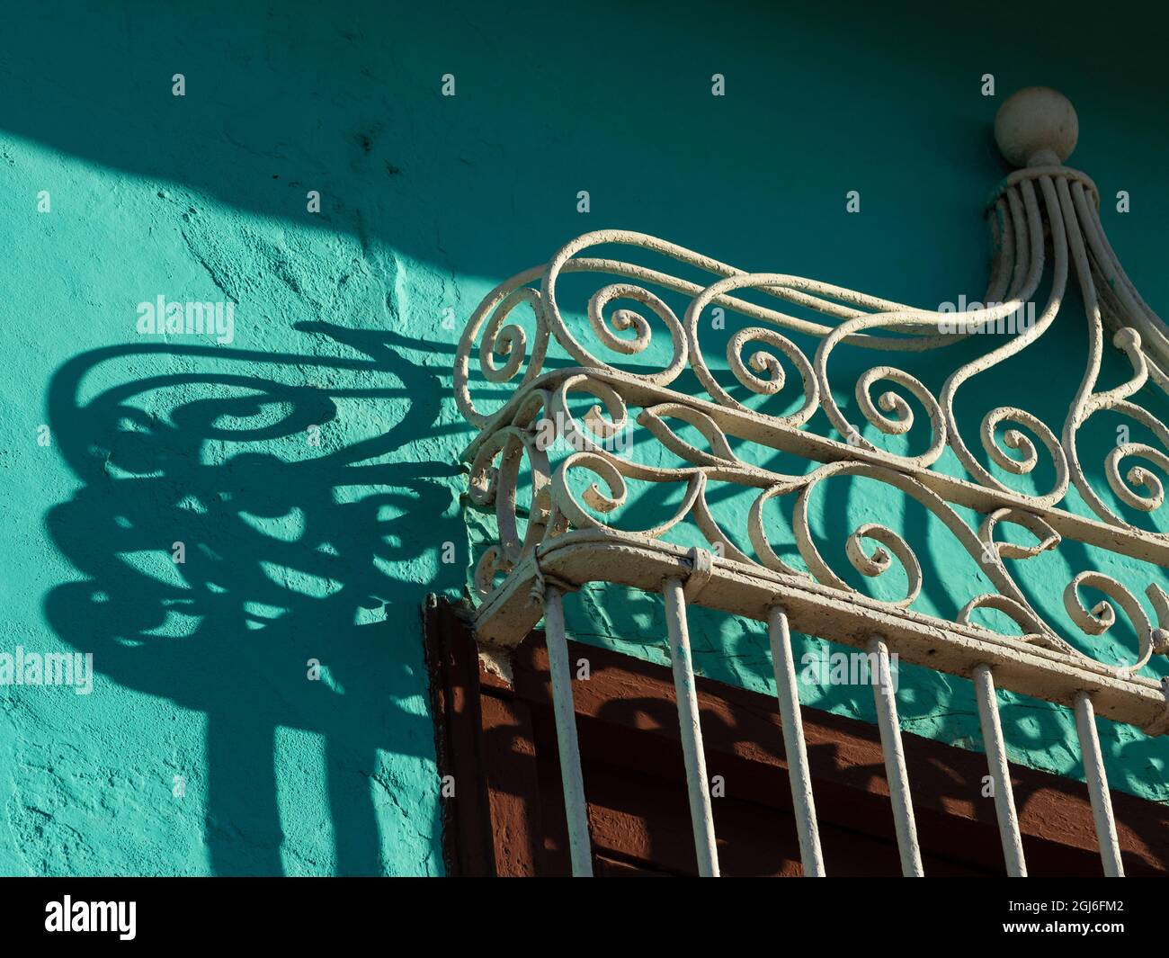 Cuba, Trinité. Grille de fenêtre en fer forgé et ombre sur un mur turquoise. Banque D'Images