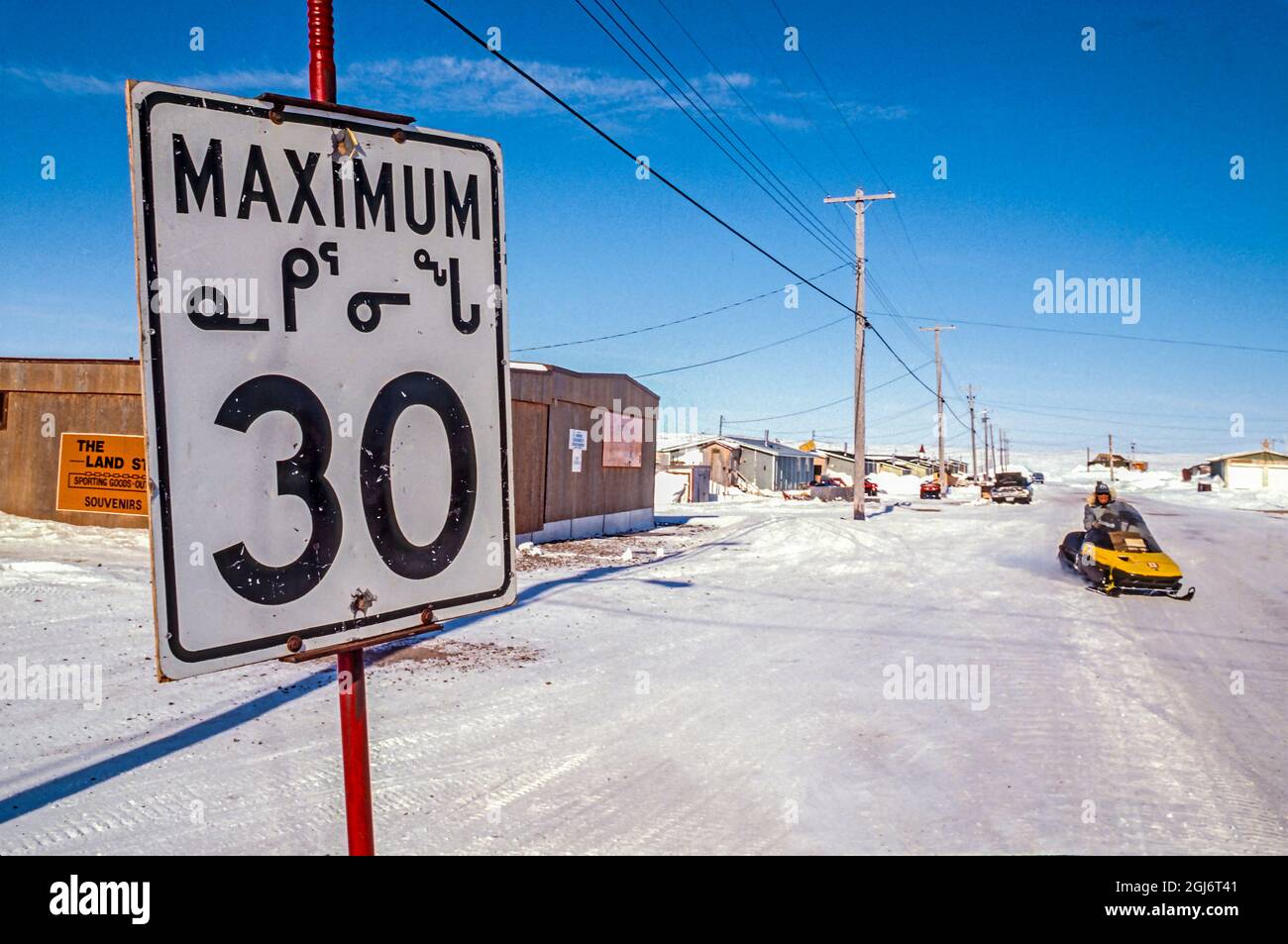 Baker Lake, Nunavut, Canada. Panneau de limite de vitesse en langue inuite (inuktitut) le long d'une rue enneigée. (Usage éditorial uniquement) Banque D'Images