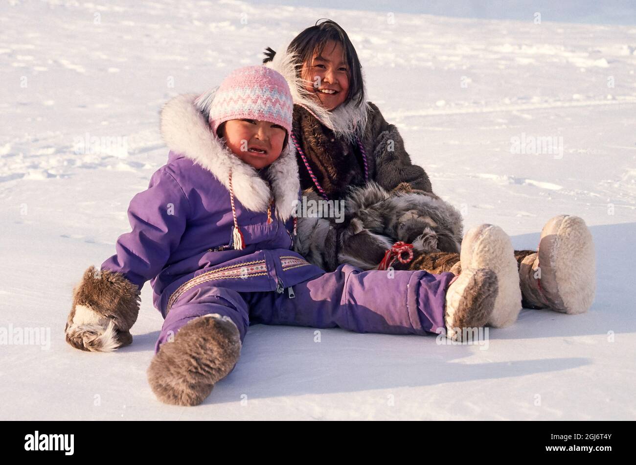 Baker Lake, Nunavut, Canada. Les filles inuites, âgées de 4 et 11 ans, sont assises sur la neige dans le camp. La fille plus âgée porte des vêtements traditionnels en peau de caribou. Le plus jeune Banque D'Images