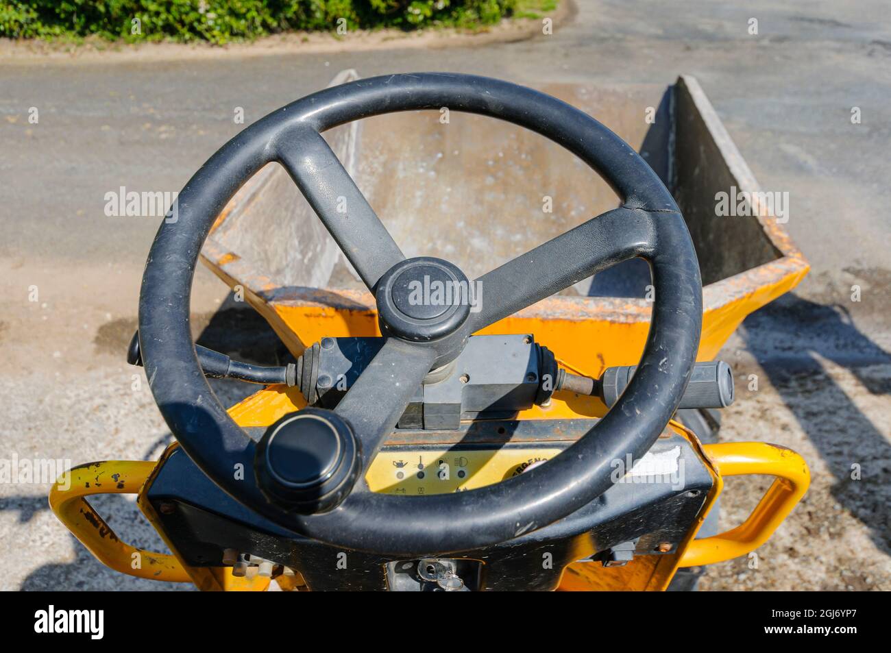 Conduite d'un mini-camion à benne basculante jaune le long d'une voie de ferme. Banque D'Images