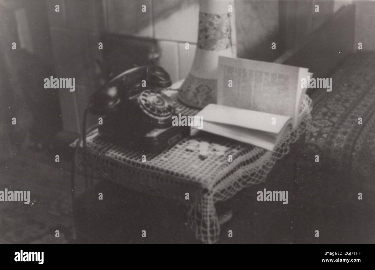Photographie d'intérieur vintage sur une table de console avec un téléphone bakélite, vase et livre (poêle en faïence à l'arrière) des années 1930 Banque D'Images