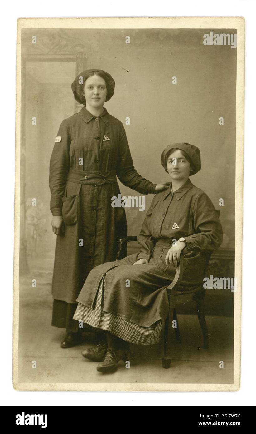 Portrait original en studio de la première Guerre mondiale d'une paire de femmes ouvrières attirantes portant des badges du ministère des munitions « en service de guerre », Londres ou Woking (Surrey), Angleterre, Royaume-Uni vers 1917 Banque D'Images