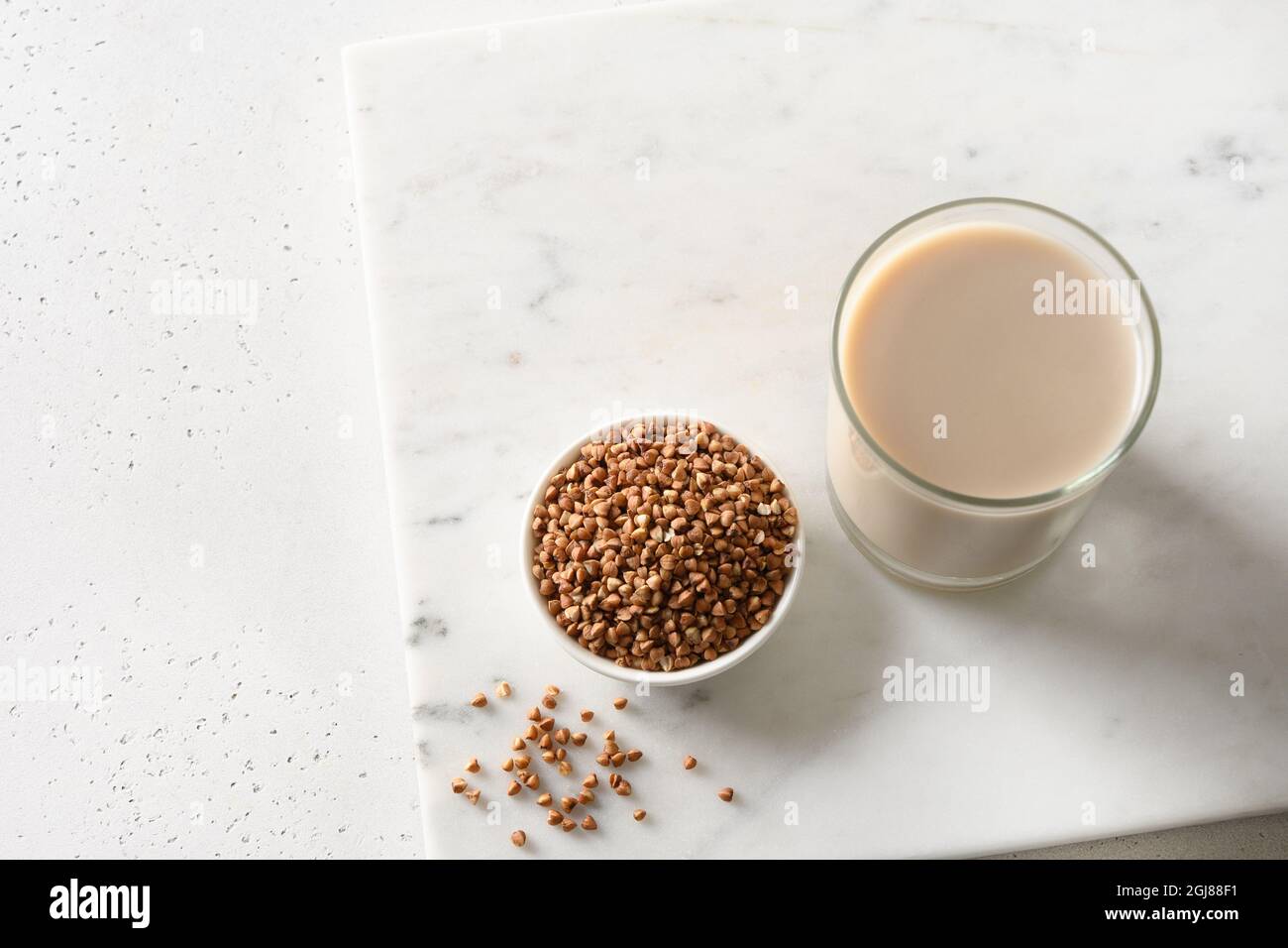 Lait de sarrasin sain sans lactose servi dans un verre à boire avec un ingrédient de grain sur fond blanc. Orientation horizontale. Copier l'espace. Banque D'Images