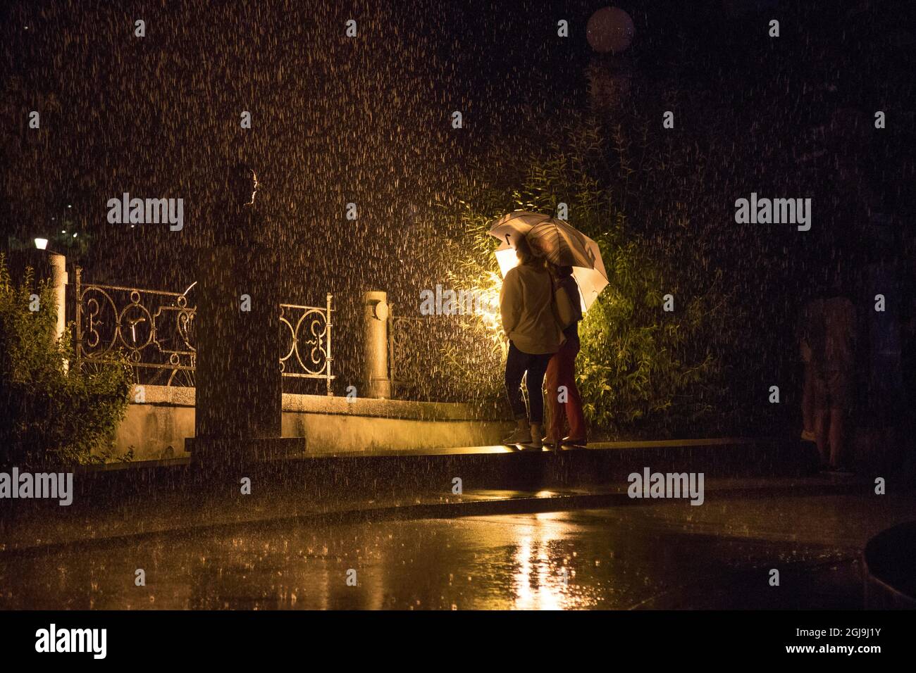 Europe, Slovénie, Ljubljana. Un couple sous la pluie la nuit. Banque D'Images