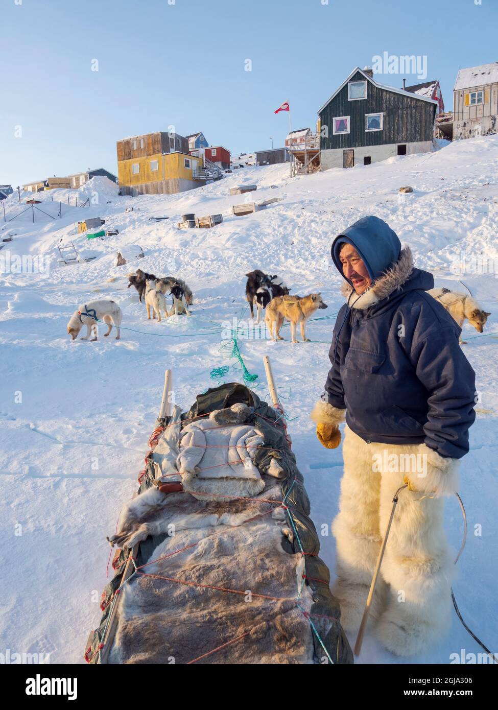 De retour de la chasse. Le chasseur porte des pantalons et des bottes traditionnels en fourrure d'ours polaire. Le village traditionnel et isolé des Inuits groenlandais Banque D'Images