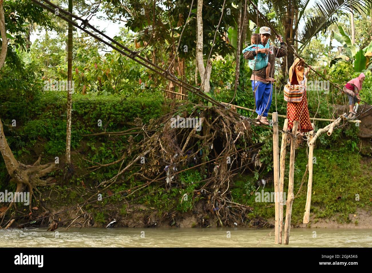 Luwu, Indonésie. 08 septembre 2021. Un résident tenant un enfant traversant une rivière en utilisant un pont gravement endommagé à Malela.même si c'est dangereux, chaque jour le pont qui a été endommagé par l'inondation est toujours utilisé par les résidents pour réduire le temps de déplacement vers d'autres villages. Crédit : SOPA Images Limited/Alamy Live News Banque D'Images