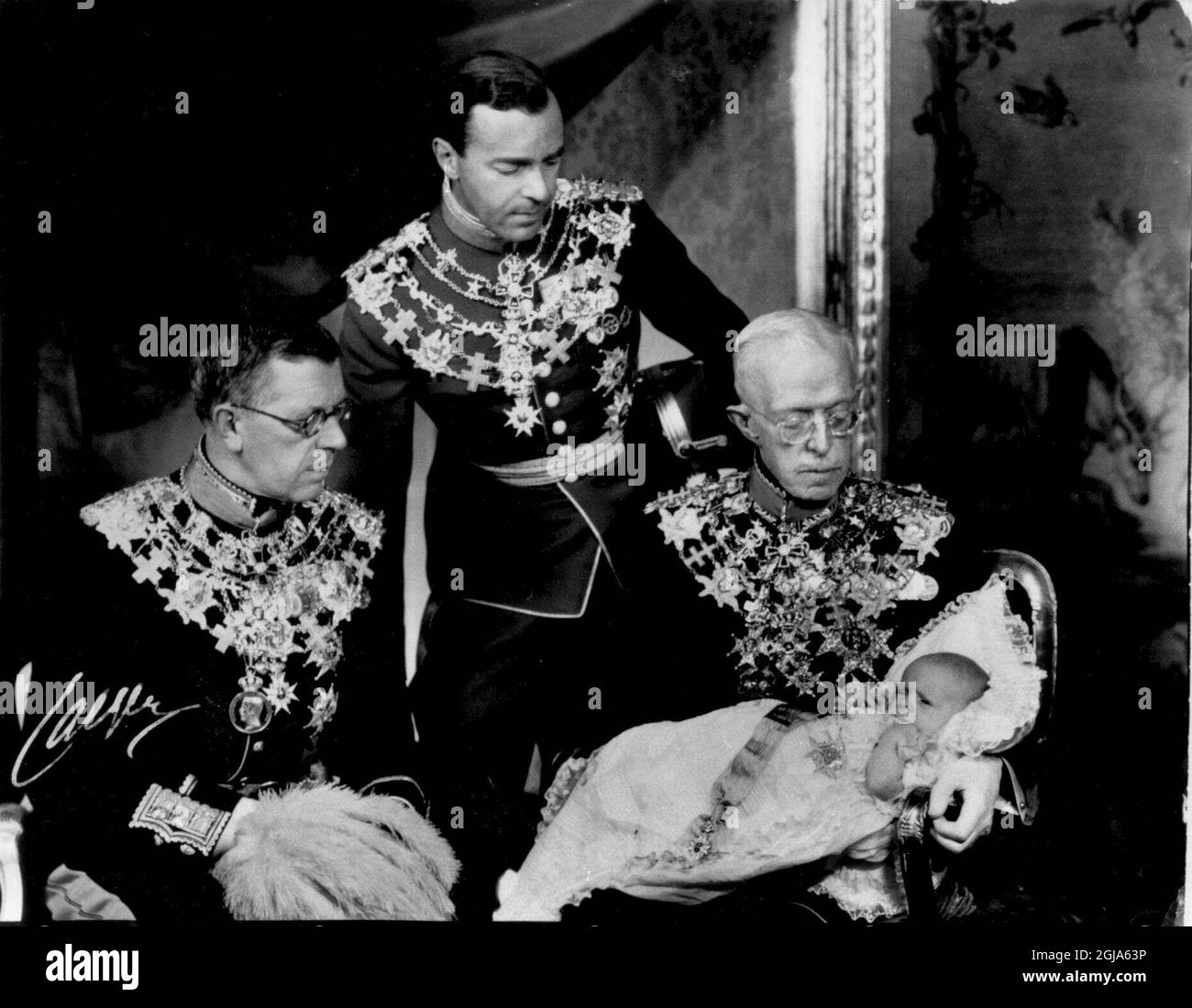 Â©SCANPIX SUÈDE, 1946-06-08. Dopet av prins Carl Gustaf. Prins Carl Gustaf i docklanning i armarna pa sin gammelfarfar kung Gustaf V. Blivande kung Gustaf VI (t.v.) och staende prinsens Far Gustaf Adolf. Foto: SCANPIX Code: 20360 *** ENGCAP: LE BAPTÊME. LE PRINCE CARL GUSTAF DANS LES BRAS DE SON GRAND-PÈRE, LE ROI GUSTAF V. EST PARTI : LE ROI À ÊTRE, GUSTAF VI, ET AU-DESSUS DU PÈRE DE CARL GUSTAF, GUSTAF ADOLF. Banque D'Images