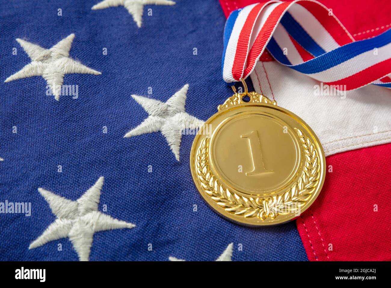 Médaille d'or pour les États-Unis. Prix du gagnant avec ruban sur fond de drapeau américain. Trophée d'athlète américain dans le sport pour la première place champion. Numéro un et la Banque D'Images