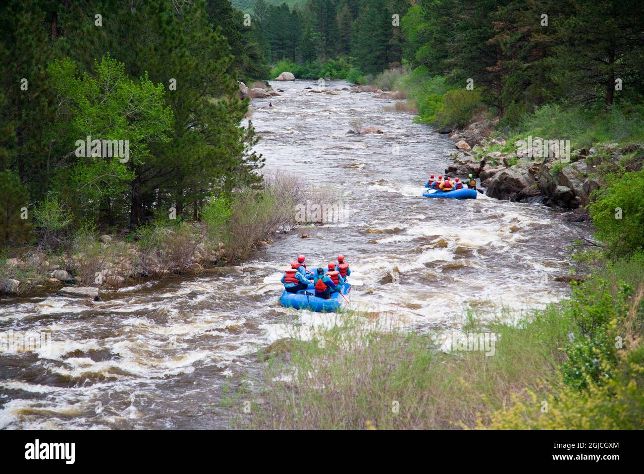 États-Unis, Colorado. La rivière cache la poudre cascade tandis que les rafters traversent l'eau vive dans le nord du Colorado. Banque D'Images