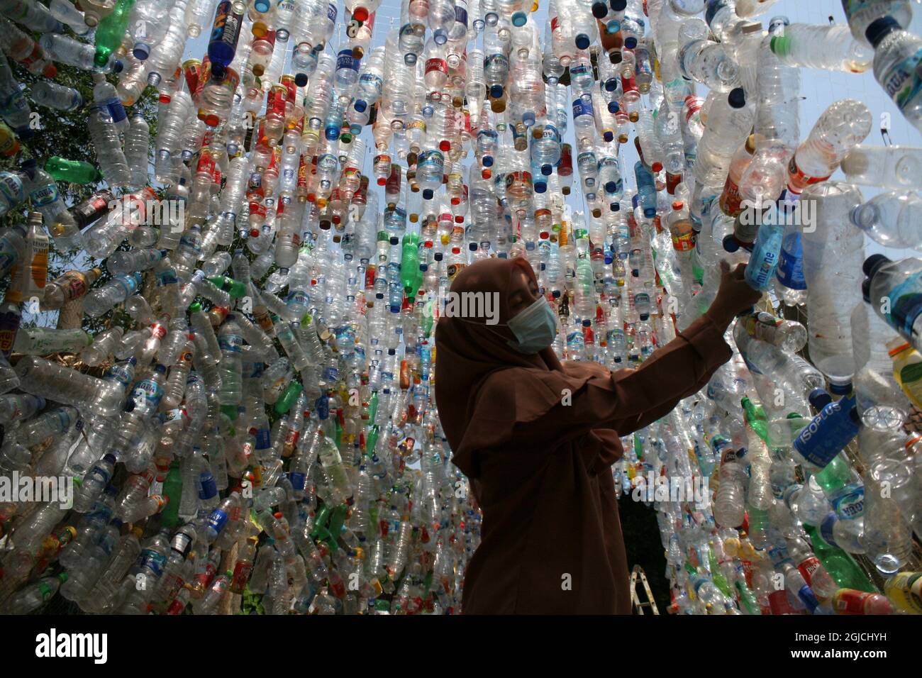 Gresik, Indonésie. 9 septembre 2021. Une femme regarde une installation avec des bouteilles en plastique lors d'une campagne environnementale à Gresik, East Java, Indonésie, le 9 septembre 2021. L'installation en plastique a été construite à partir de garbages en plastique recueillis dans les rivières de Gresik et de Surabaya. Credit: Kurniawan/Xinhua/Alay Live News Banque D'Images