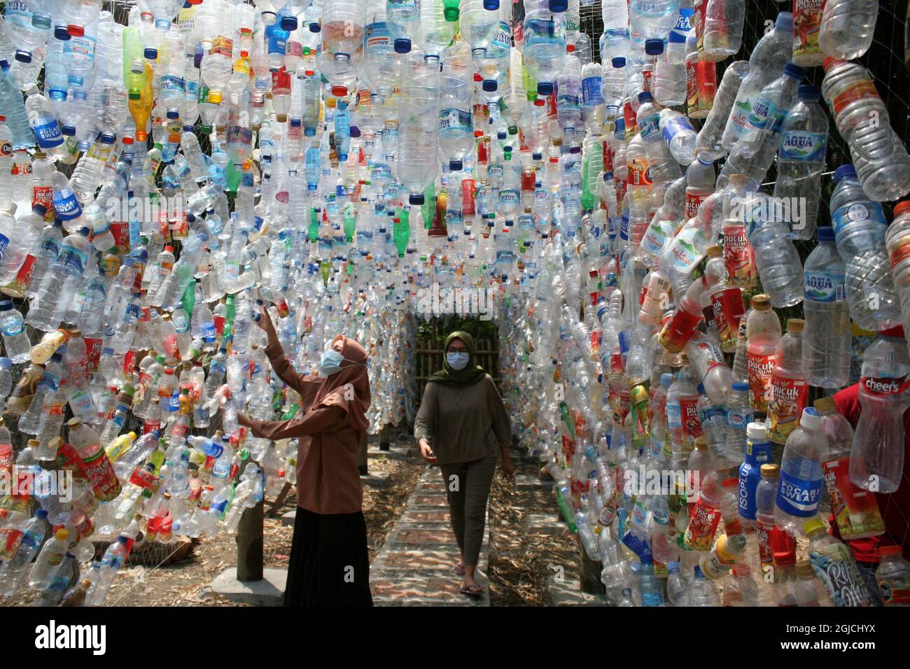 Gresik, Indonésie. 9 septembre 2021. Des gens traversent une installation avec des bouteilles en plastique lors d'une campagne environnementale à Gresik, East Java, Indonésie, le 9 septembre 2021. L'installation en plastique a été construite à partir de garbages en plastique recueillis dans les rivières de Gresik et de Surabaya. Credit: Kurniawan/Xinhua/Alay Live News Banque D'Images