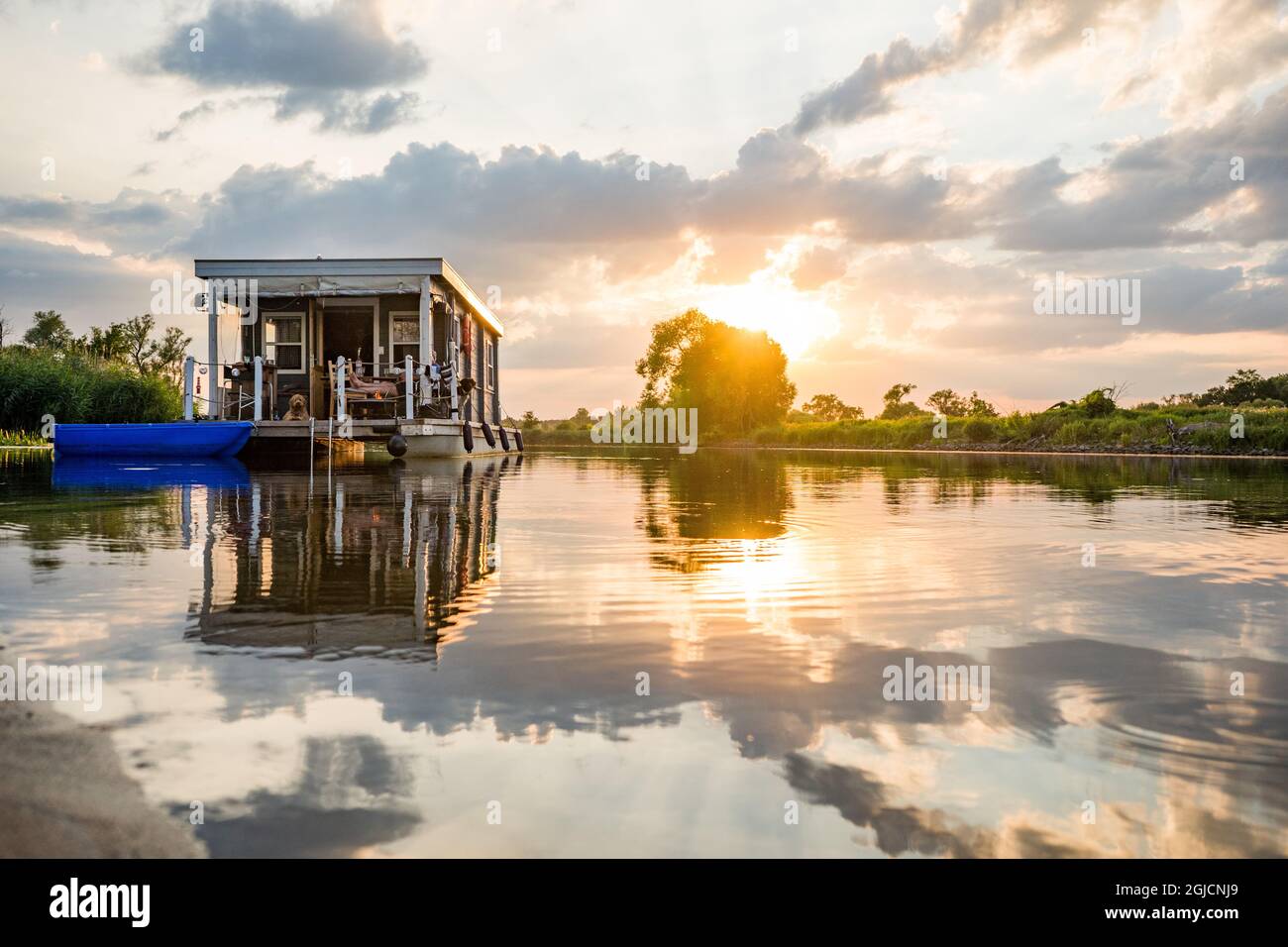 péniche aménagée sur une rivière au coucher du soleil Banque D'Images