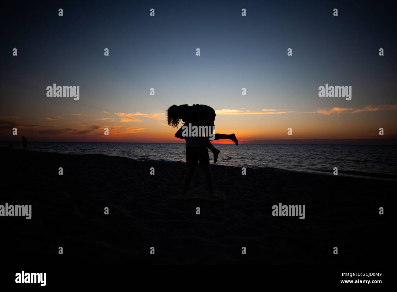 Silhouette d'un couple ayant plaisir et joie sur la plage à avec coucher de soleil ciel et mer en arrière-plan Banque D'Images