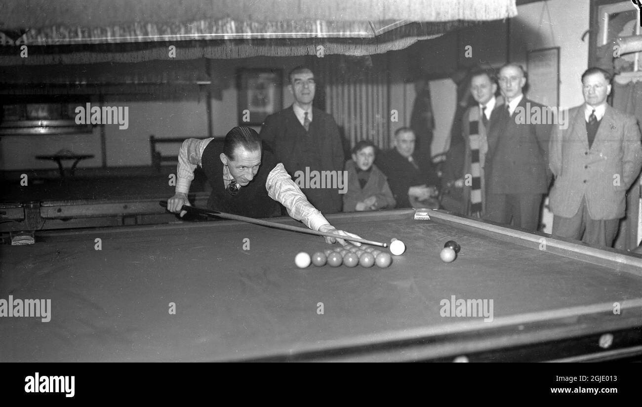 1948, historique, à l'intérieur d'un club de snooker, les hommes regardent un joueur de snooker sur le point de faire du pot, Witney, Oxford, Angleterre, Royaume-Uni. Banque D'Images