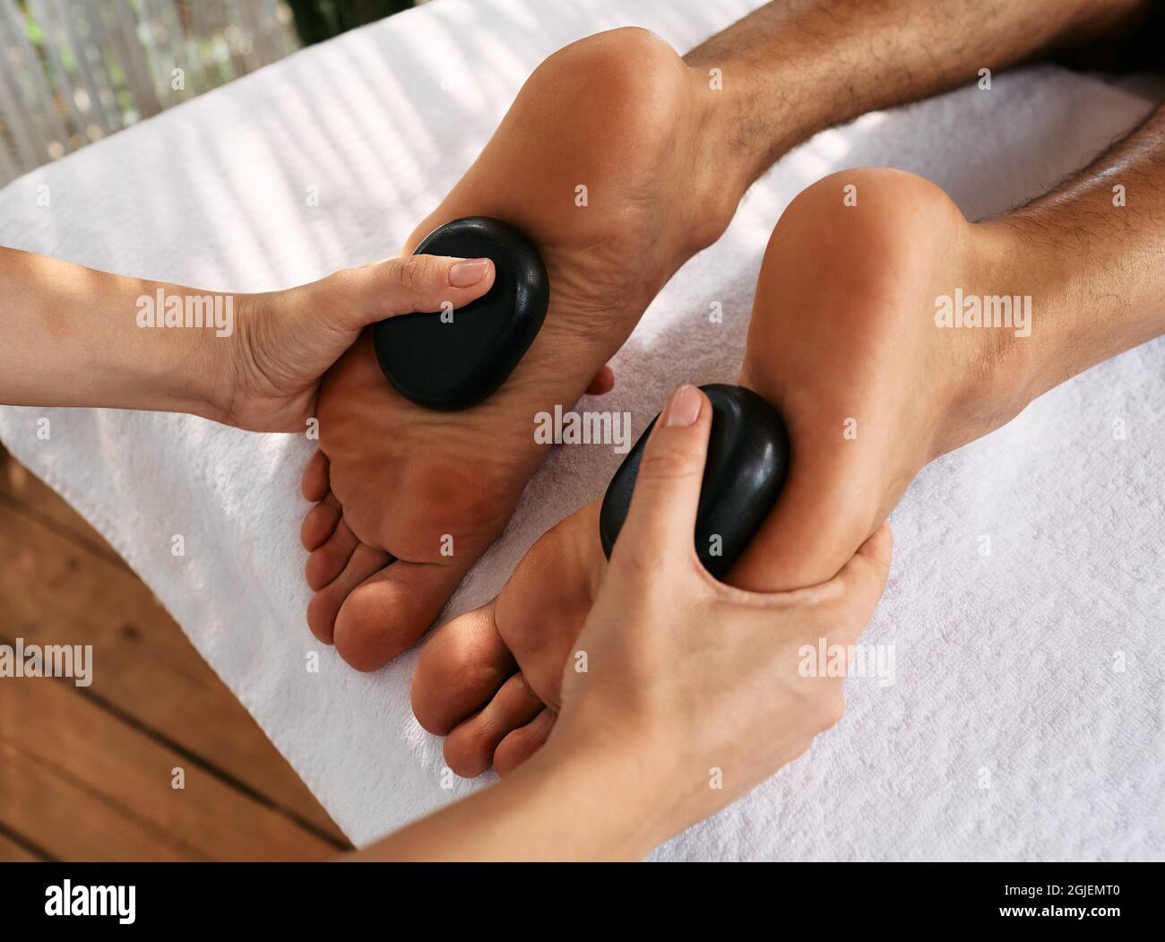 Massage Des Pieds Aux Pierres Chaudes Massotherapeute Effectuant Un Massage Des Pieds En Pierre Chaude Pour Les Pieds Des Hommes Au Spa Photo Stock Alamy