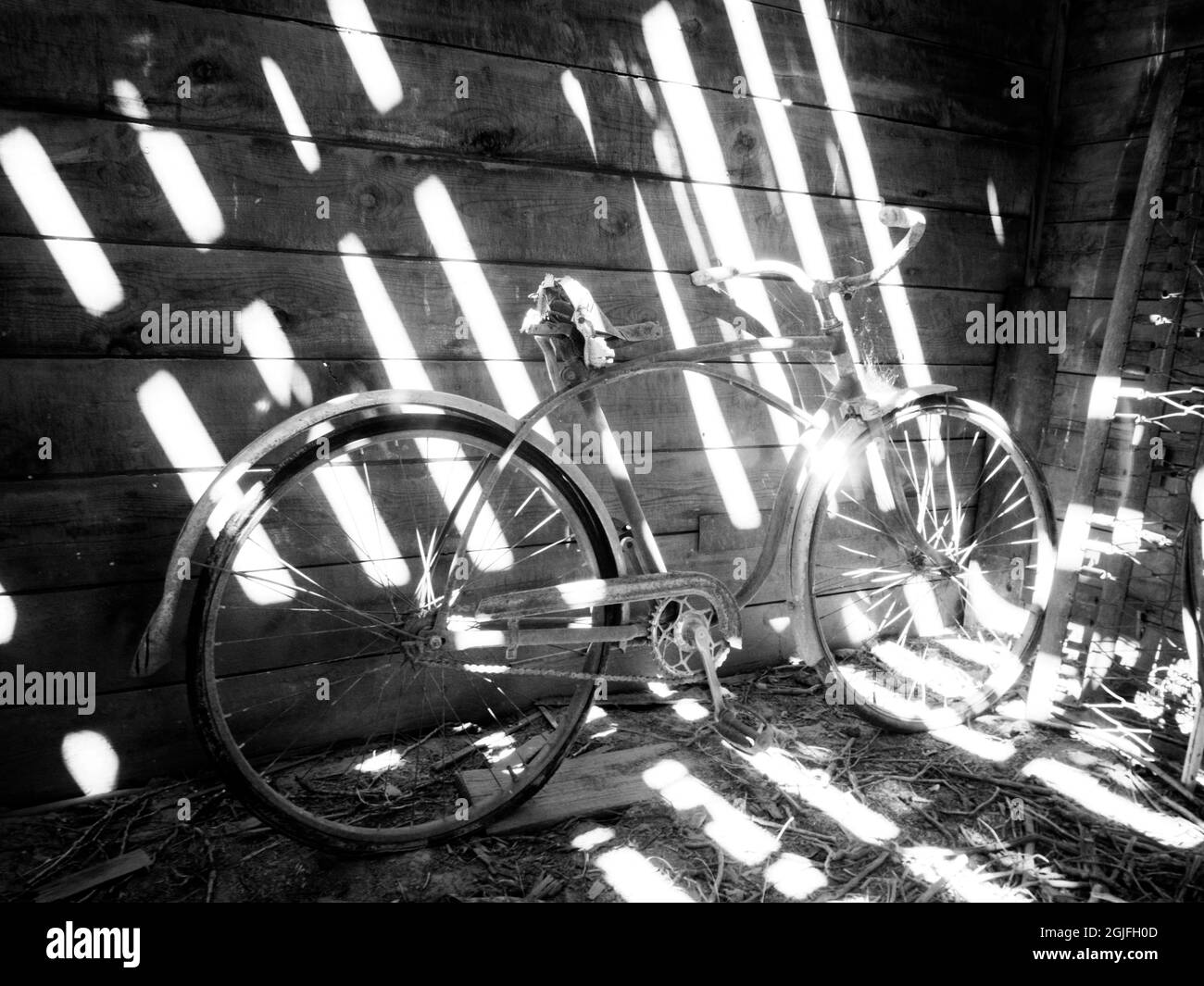 Vieux vélo à l'intérieur de la grange avec des ombres en streaming. Banque D'Images