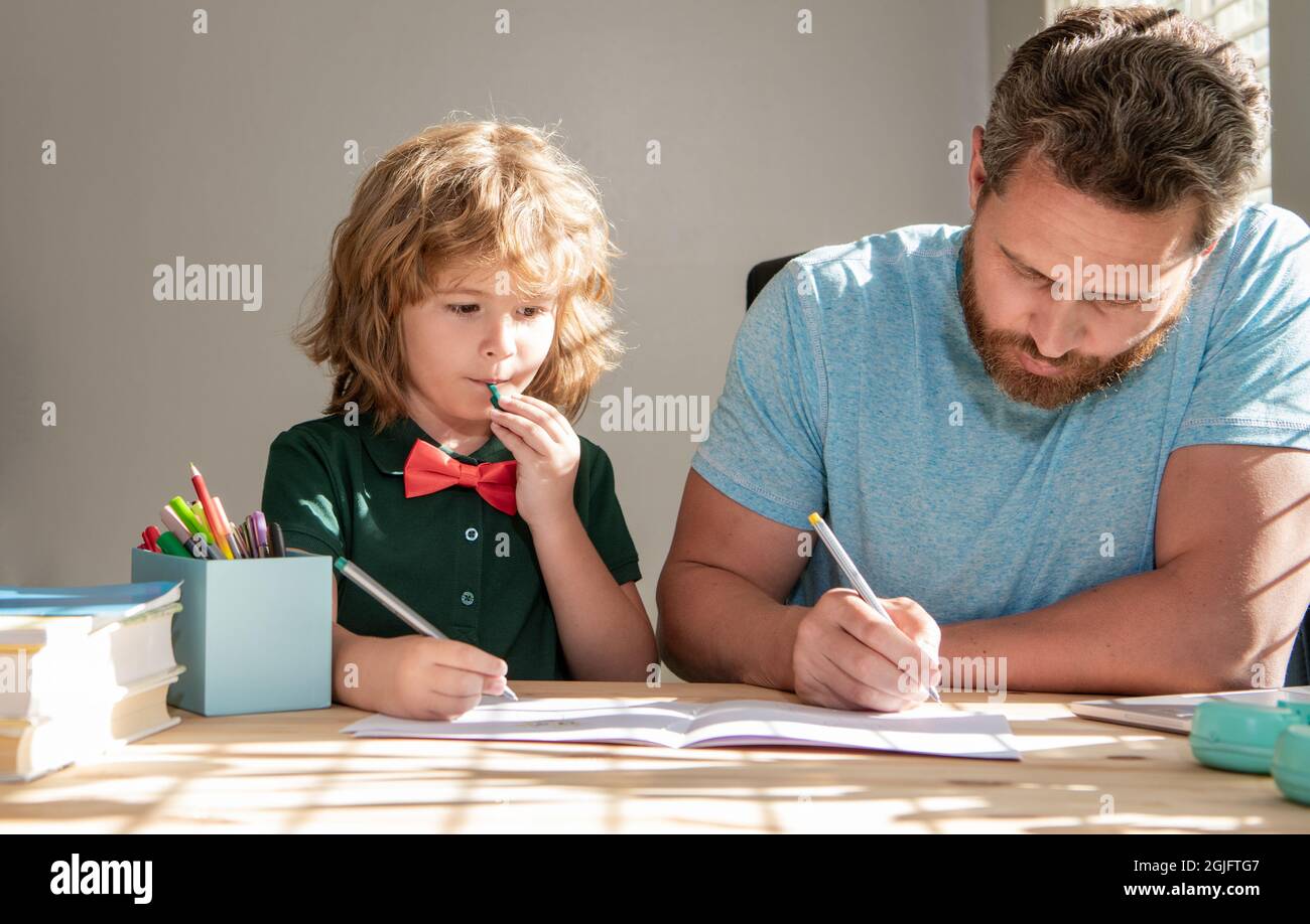 le père barbu écrit ses devoirs à l'école avec son fils garçon en classe, à l'école Banque D'Images