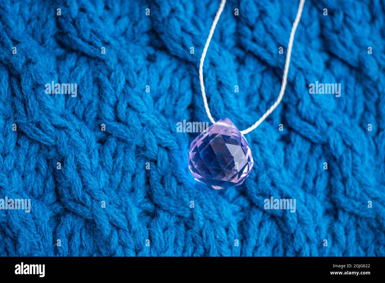 Grand cristal rose avec fil sur un motif tricoté bleu. Banque D'Images