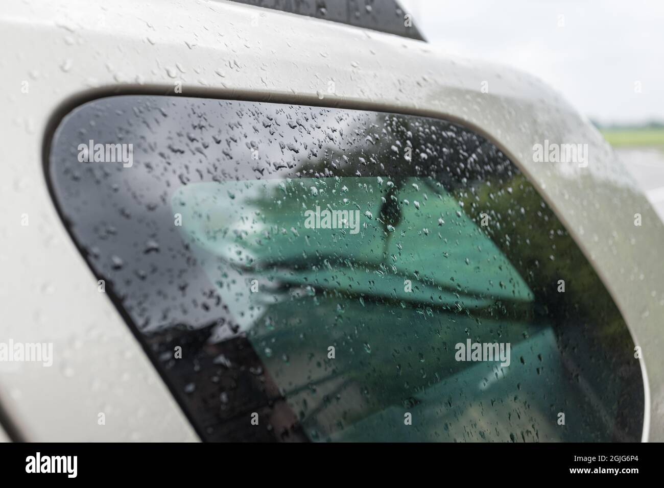 Gouttes de pluie sur la vitre et le capot de la voiture. Gros plan des gouttes d'eau après la pluie à la fenêtre de la voiture. Pluie de saison. Banque D'Images