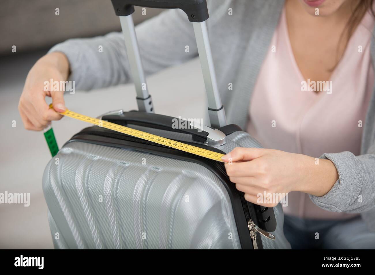 femme inspectant la mesure des bagages à main à l'aide d'un ruban de mesure Banque D'Images