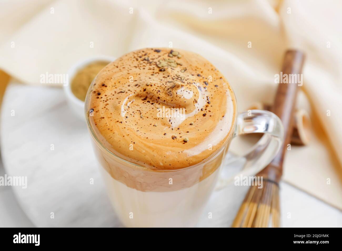 Tasse en verre de délicieux Dalgona hojicha latte sur table, gros plan Banque D'Images