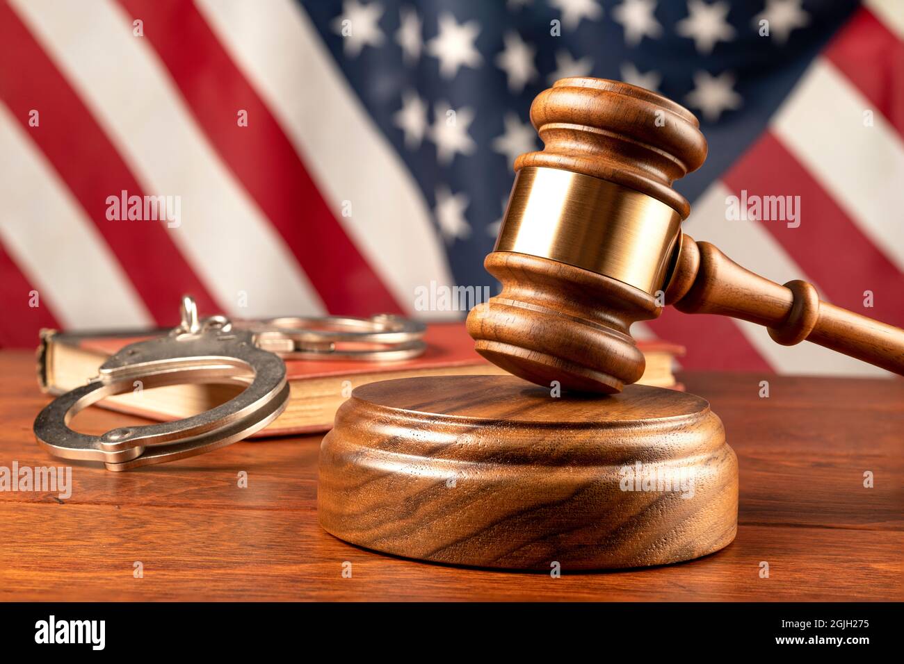 Un gavel et un bloc de bois reposent sur le bureau d'un juge avec un livre légal et un fond de drapeau américain. Banque D'Images