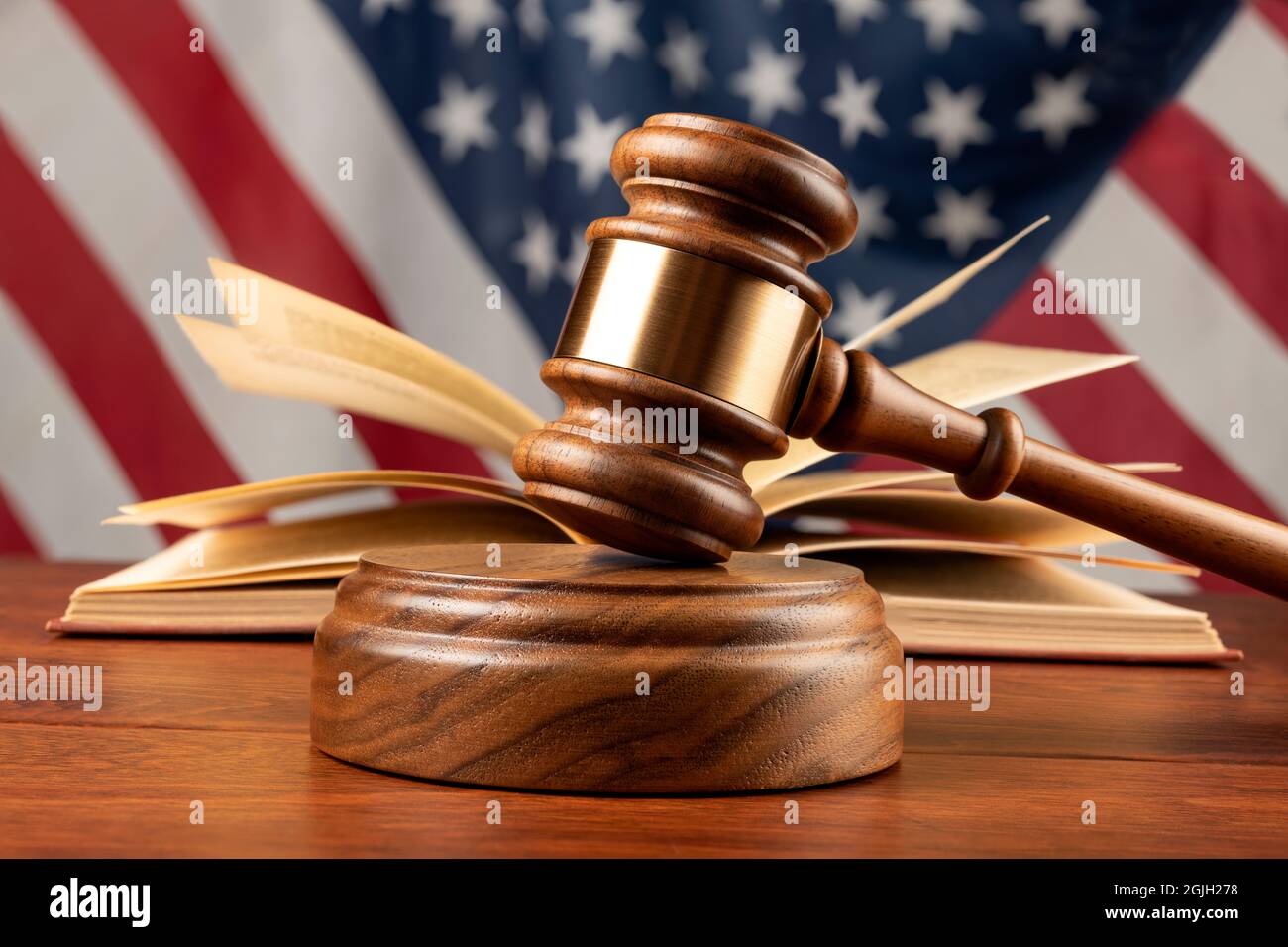 Un gaval et un bloc de bois reposent sur le bureau d'un juge avec un livre et un drapeau américain. Banque D'Images