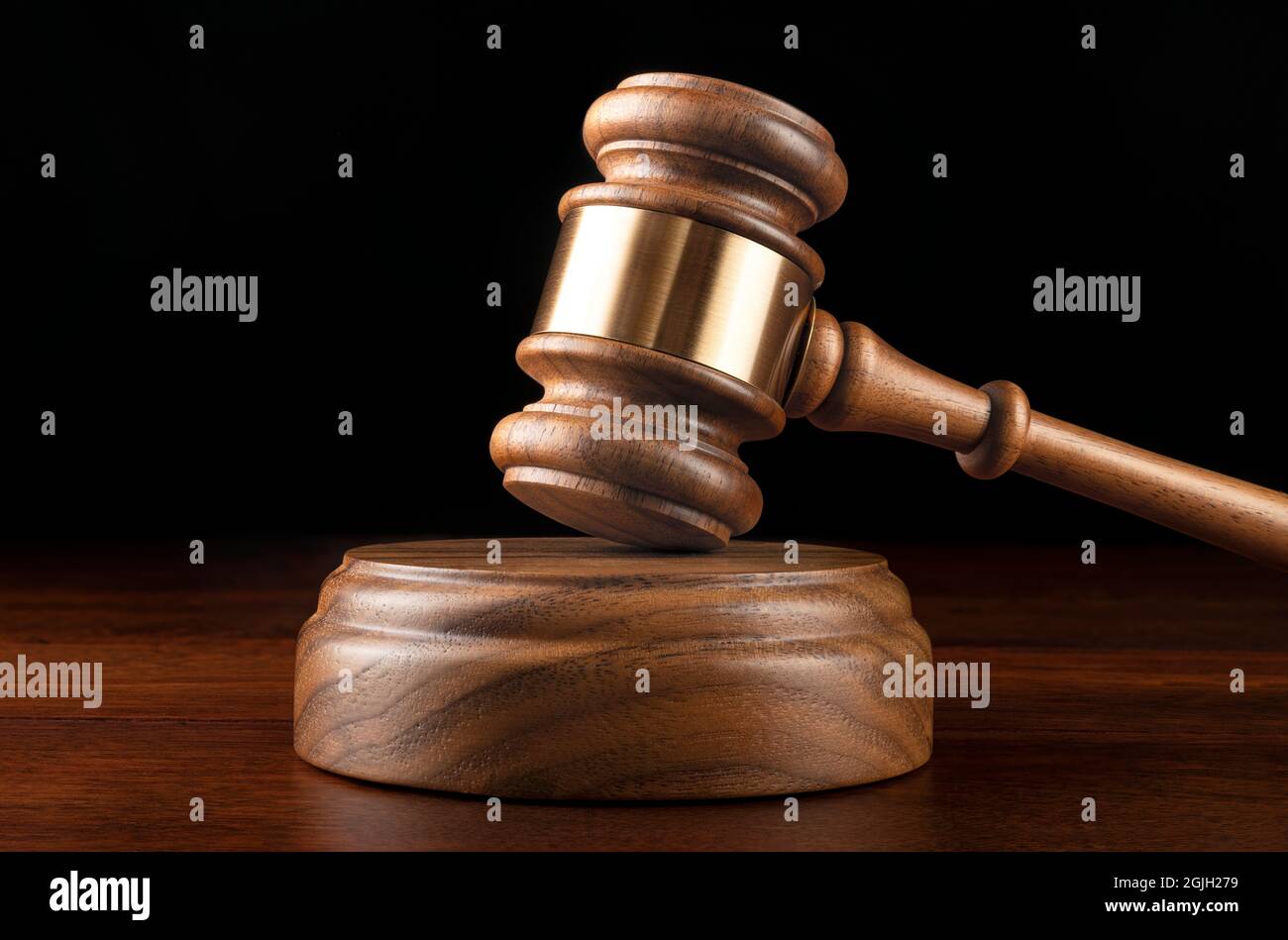 Un gavel et un bloc de bois reposent sur le bureau d'un juge avec un fond noir pour le placement de la copie. Banque D'Images
