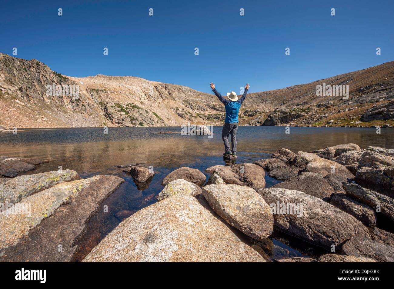 Un randonneur aventureux se dresse sur un petit rocher au lac Ptarmigan, un lac alpin isolé et moins visité dans le parc national des montagnes Rocheuses, Colorado, États-Unis Banque D'Images