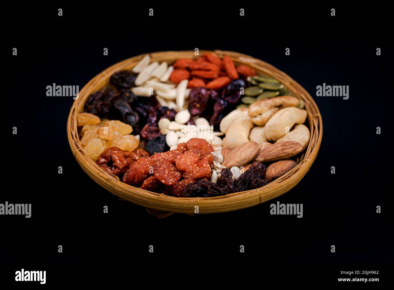 Groupe de différents types de fruits secs et séchés sur un plateau en bambou sur fond noir. Banque D'Images Groupe de différents types de fruits secs et séchés sur un plateau en bambou sur fond noir. Banque D'Images