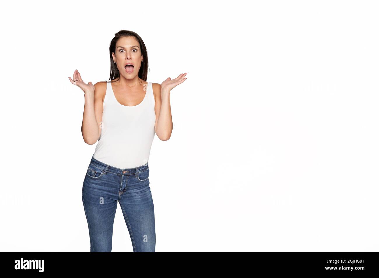 Belle femme surprise sur un arrière-plan isolé et doux regardant la caméra. Femme en Jean et t-shirt blanc sans manches. Photo de haute qualité Banque D'Images