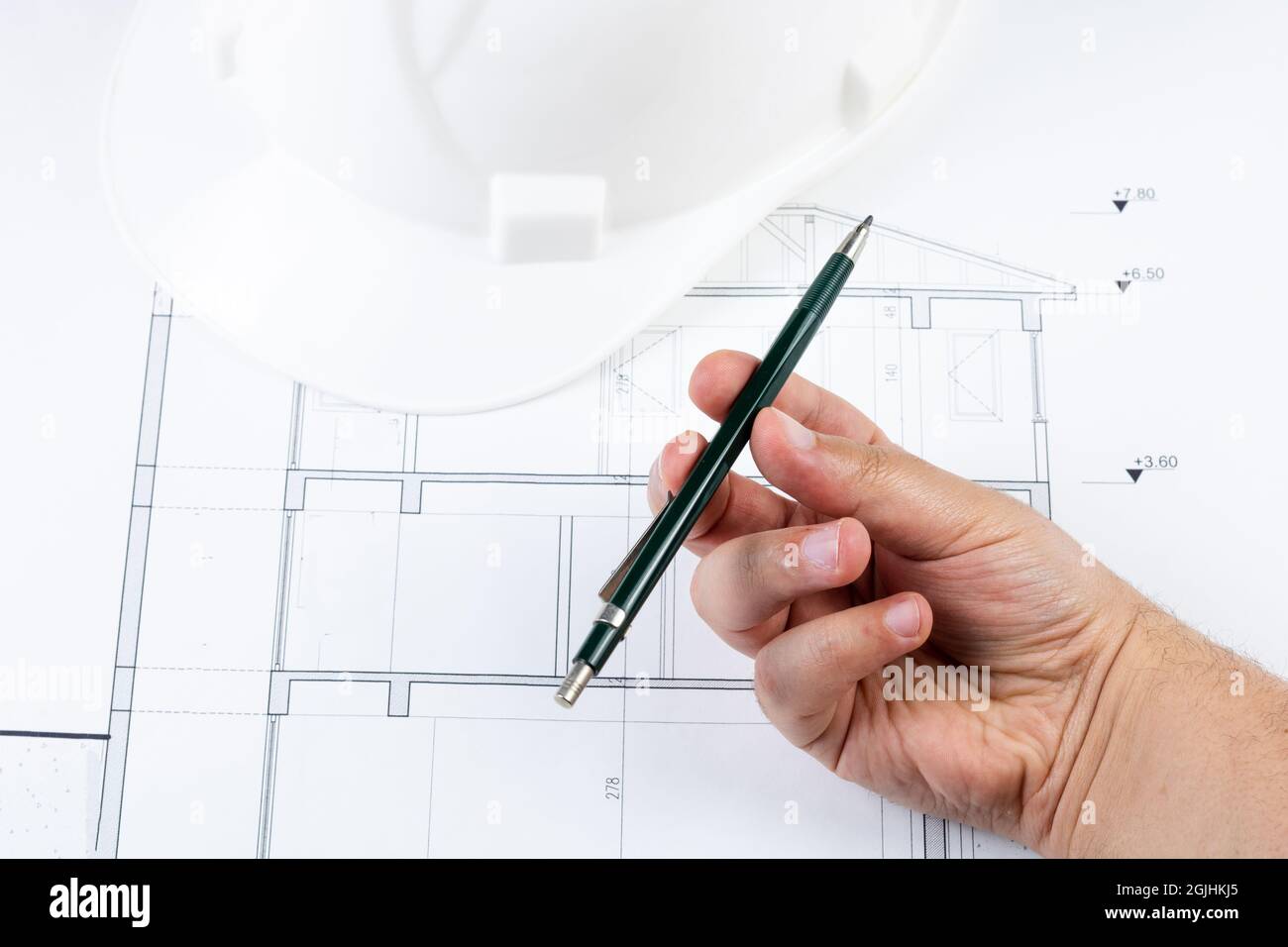 Faire tourner un stylo sur le plan architectural avec un casque de sécurité  blanc Photo Stock - Alamy