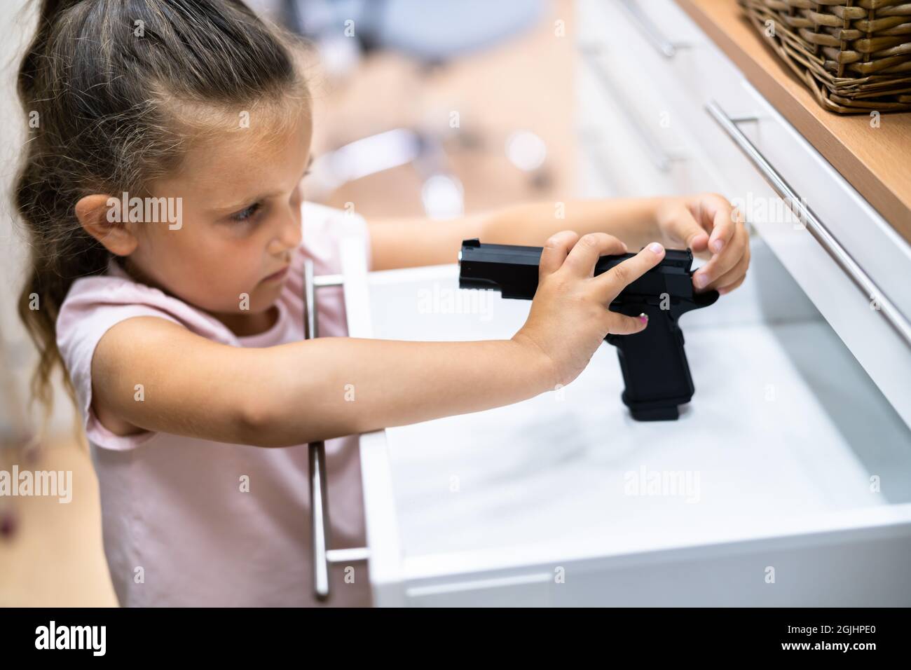 Enfant avec pistolet. Une fille qui se présente pour un pistolet dans un tiroir. Sécurité des enfants Banque D'Images