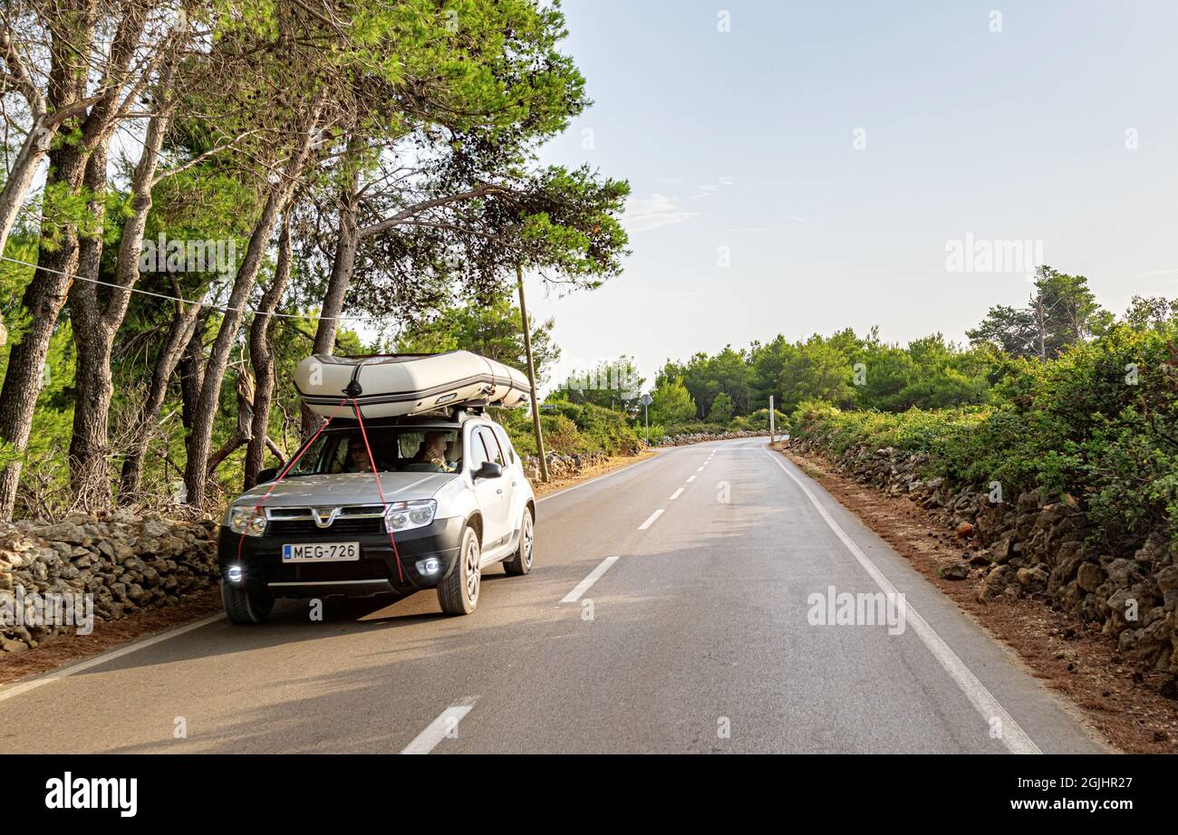 Duster Dacia sur la route avec un bateau sur le toit de l'île de Vir, Croatie. Banque D'Images